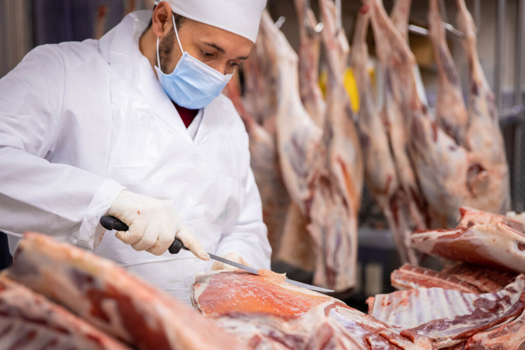 meat processing worker cutting meat