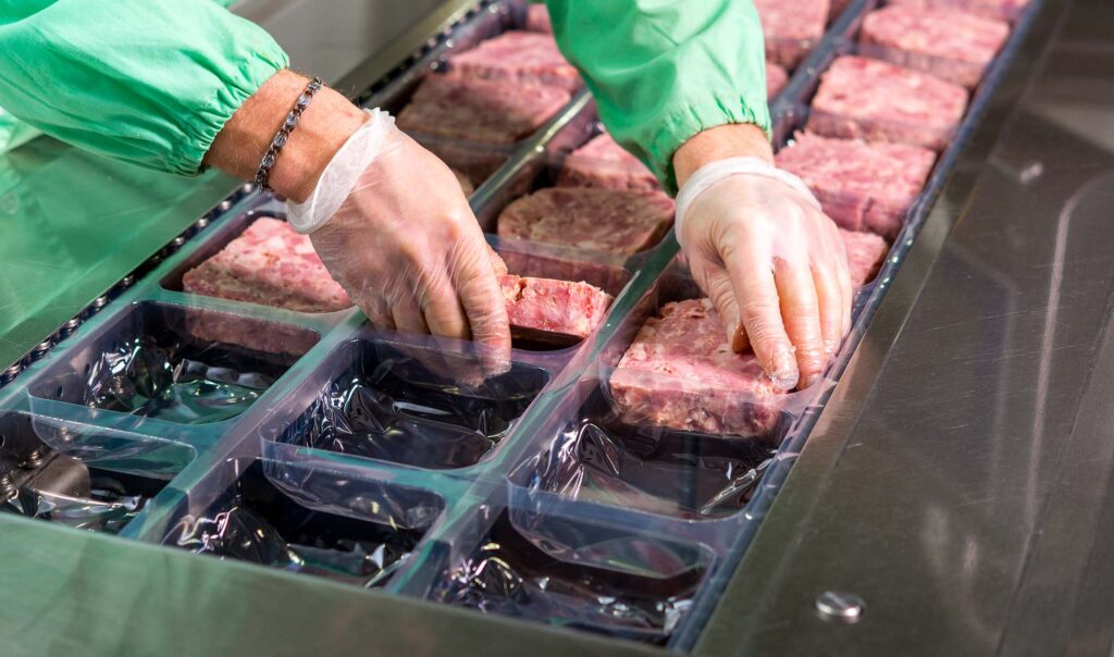 person putting ground meat into packages